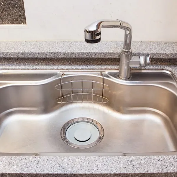 A stainless steel kitchen sink with a chrome faucet, representing a typical area for blocked sinks.