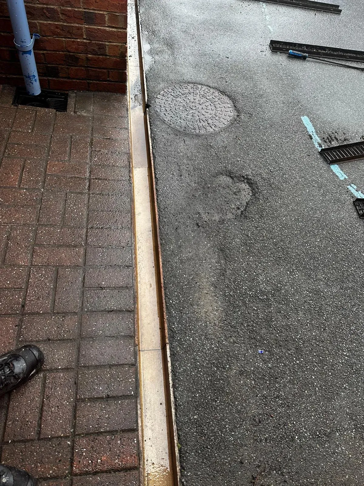 A picture of an external drain system with a manhole, channel drain, and gulley, indicating a blocked drain or recent unblocking service.