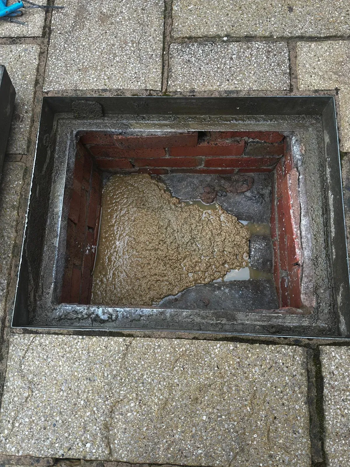 A severely blocked outdoor drain or manhole, overflowing with sludge.